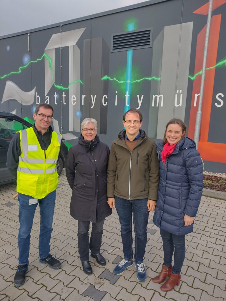 Ganzkörperfoto von vier Personen, im Hintergrund ist der Schriftzug "batterycitymüns[ter]" zu erkennen.