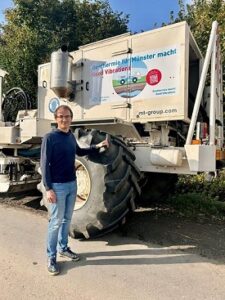 Robin steht vor einem großen weißen Vibrotruck.