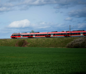 roter Zug, im Vordergrund Grüne Wiese.