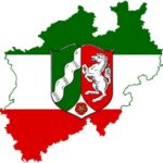 in Landesfarben eingefärbter Umriss von NRW, in der Mitte das Landeswappen